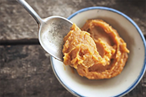 Top view of a bowl of miso with a spoon hovering over